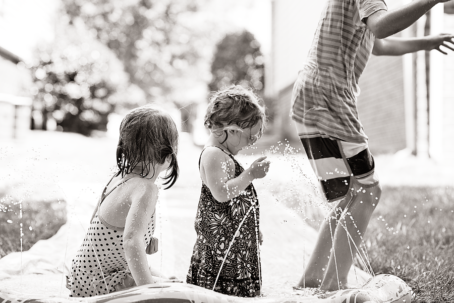 Siblings playing on a Slip and Slide. - black and white photo. Taken by Dripping Springs TX based Lydia Teague Photography. 