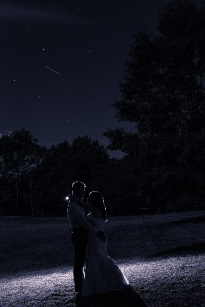 Backlit photo of a Bride and Groom with a shooting star in the sky.