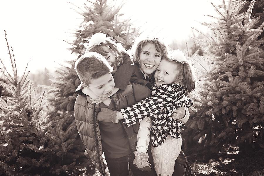 Group hug with Mom and 3 kids at a Christmas Tree Farm, photographed by Dripping Springs Texas based Lydia Teague Photography.