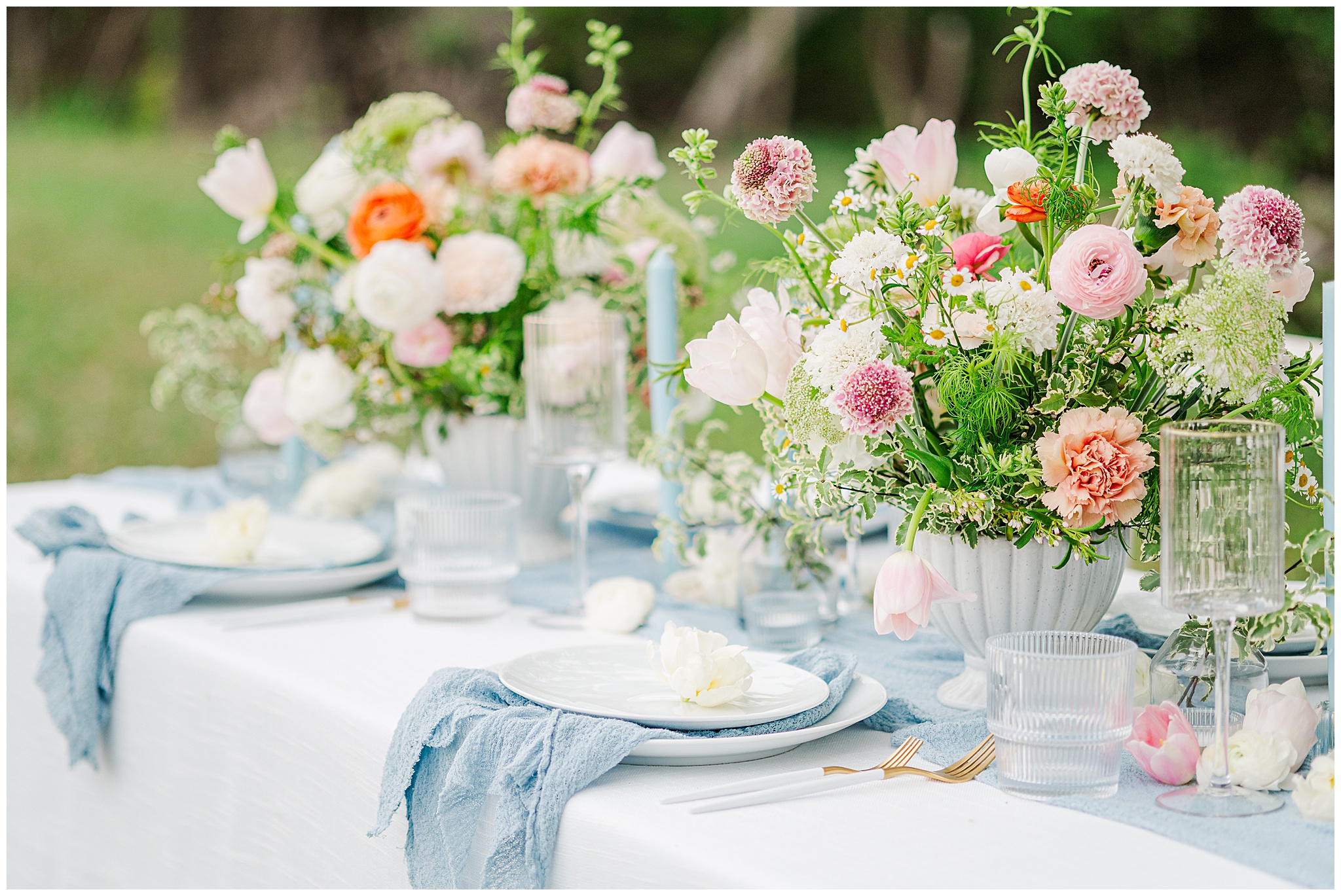 Floralscape with pinks, oranges, and peach flowers with a light blue table runner. Photo taken by Dripping Springs TX based Lydia Teague Photography.