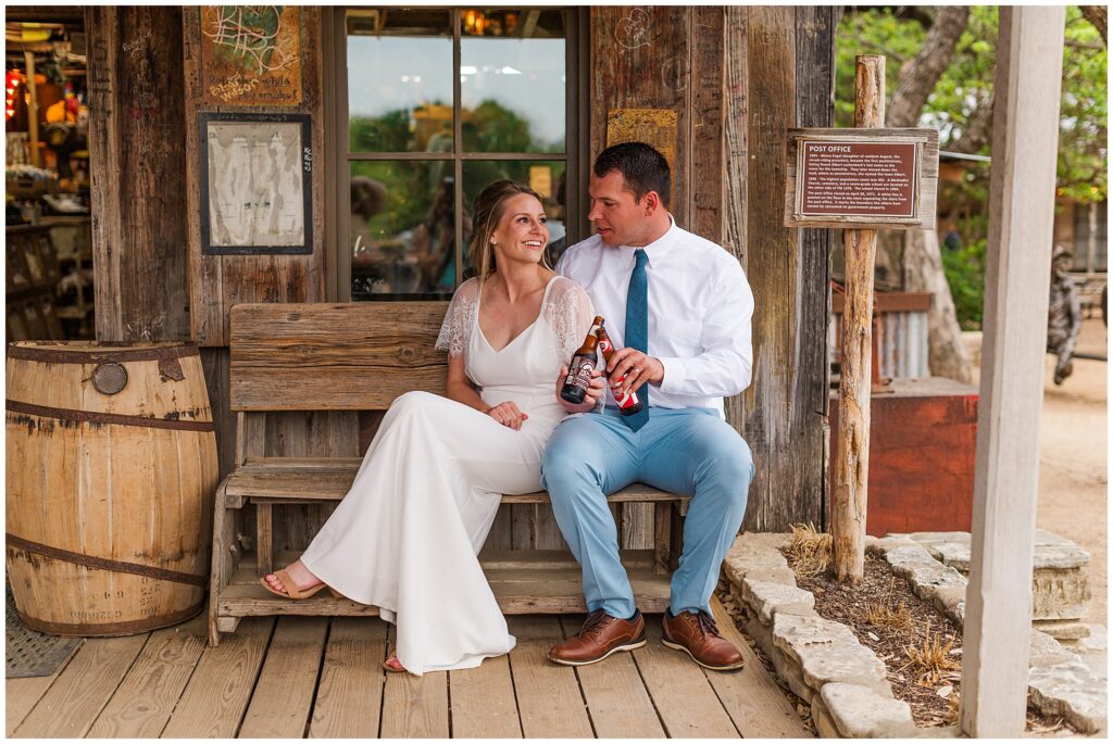 A Bride and Groom sit outside the Luckenbach Post Office and toast to their future. Photo taken by Dripping Springs TX based Lydia Teague Photography. 