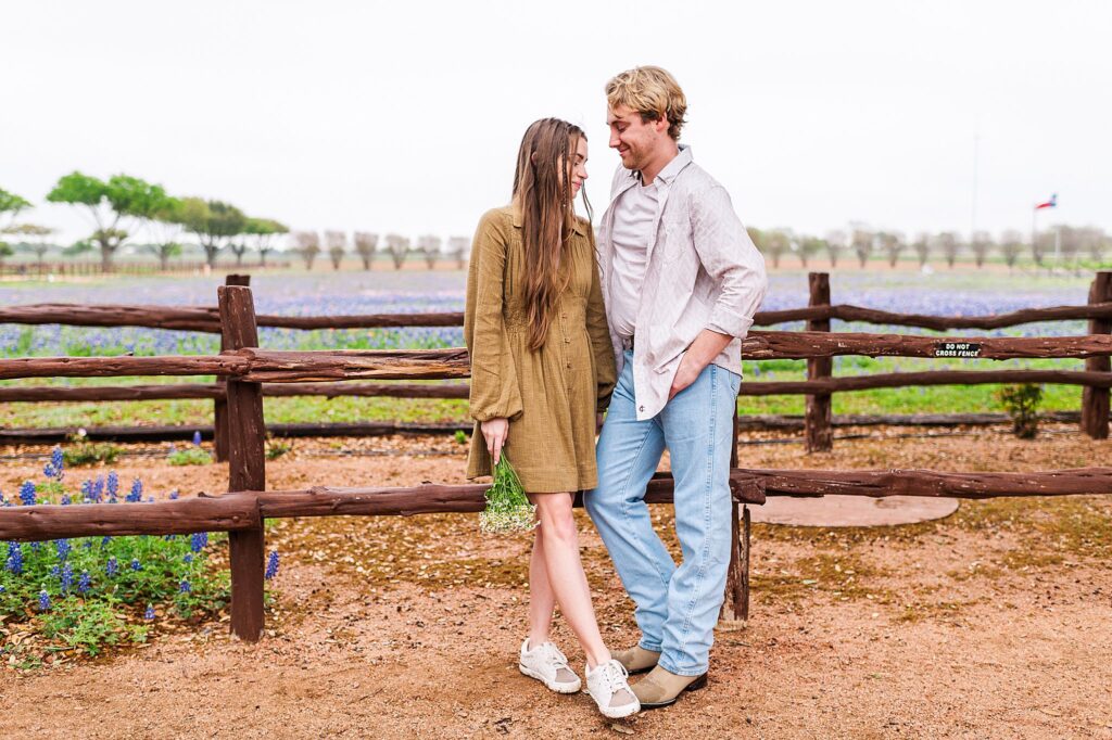 Young Couple leaning against a wood fence at a flower farm in the Texas Hill Country. Photo taken by Dripping Springs TX based Lydia Teague Photography. 