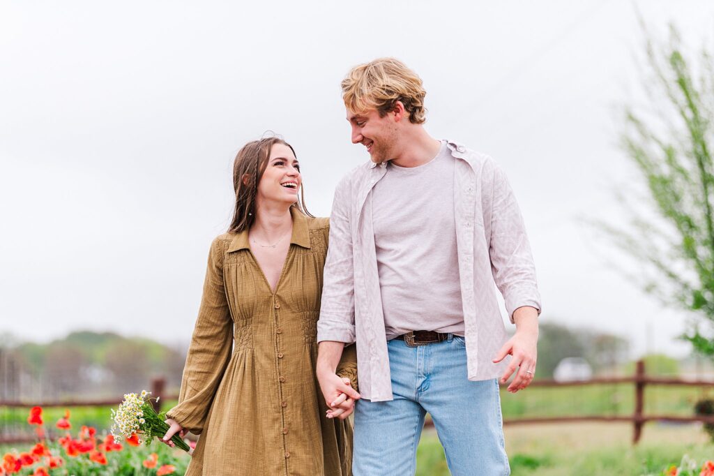 Young engaged couple walking in the rain during their engagement session at a hill country texas flower farm. photo taken by Dripping Springs TX based Lydia Teague Photography. 